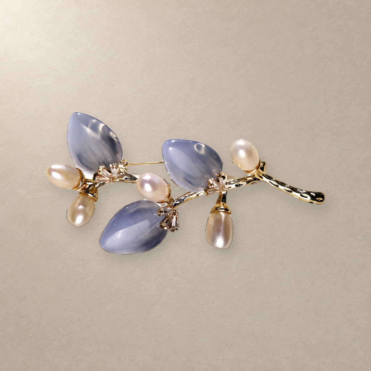 Blue cat-eye stone flower branch brooch with freshwater pearls on a neutral background