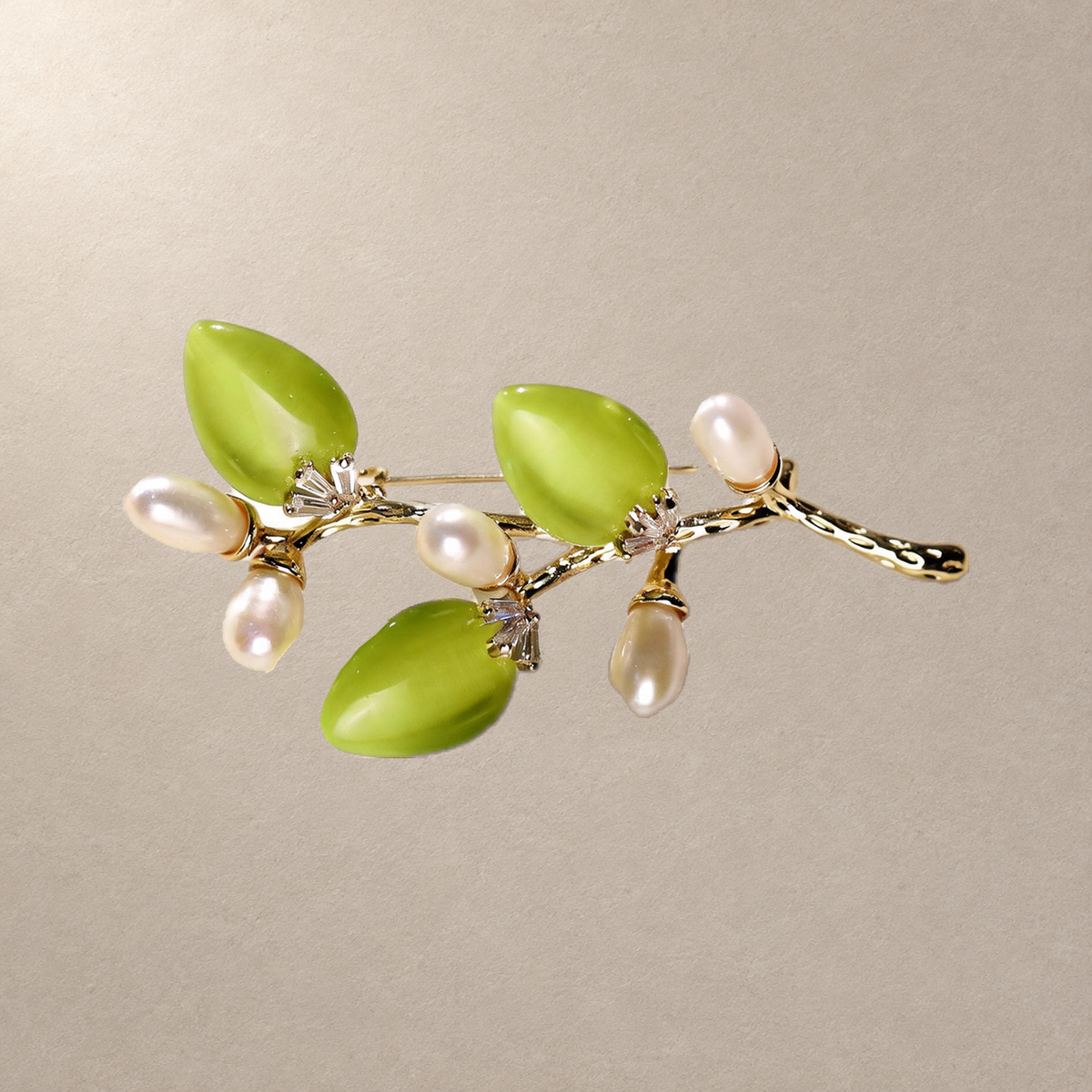 Green cat-eye stone flower branch brooch with freshwater pearls on a neutral background