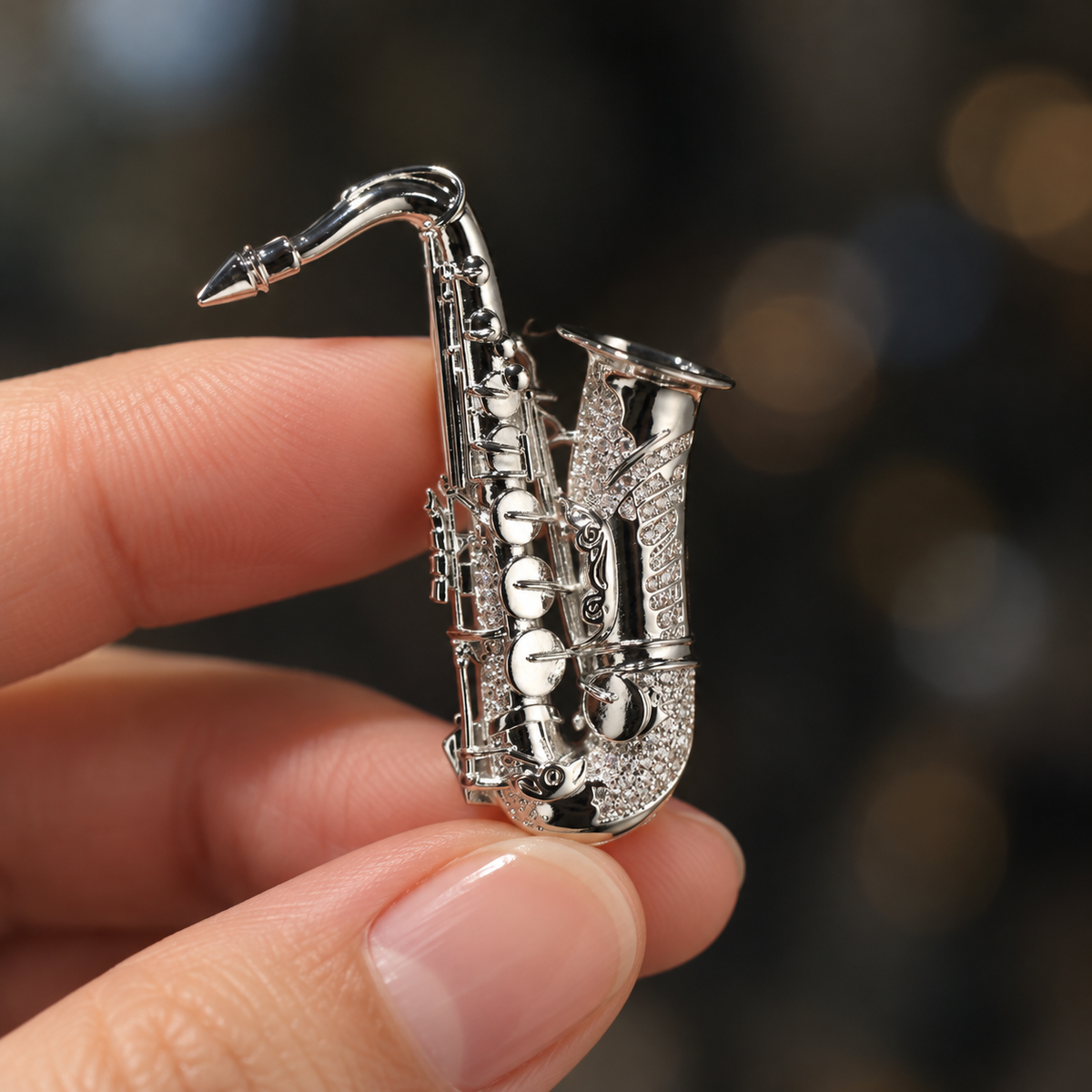 Silver tone saxophone brooch held in a hand