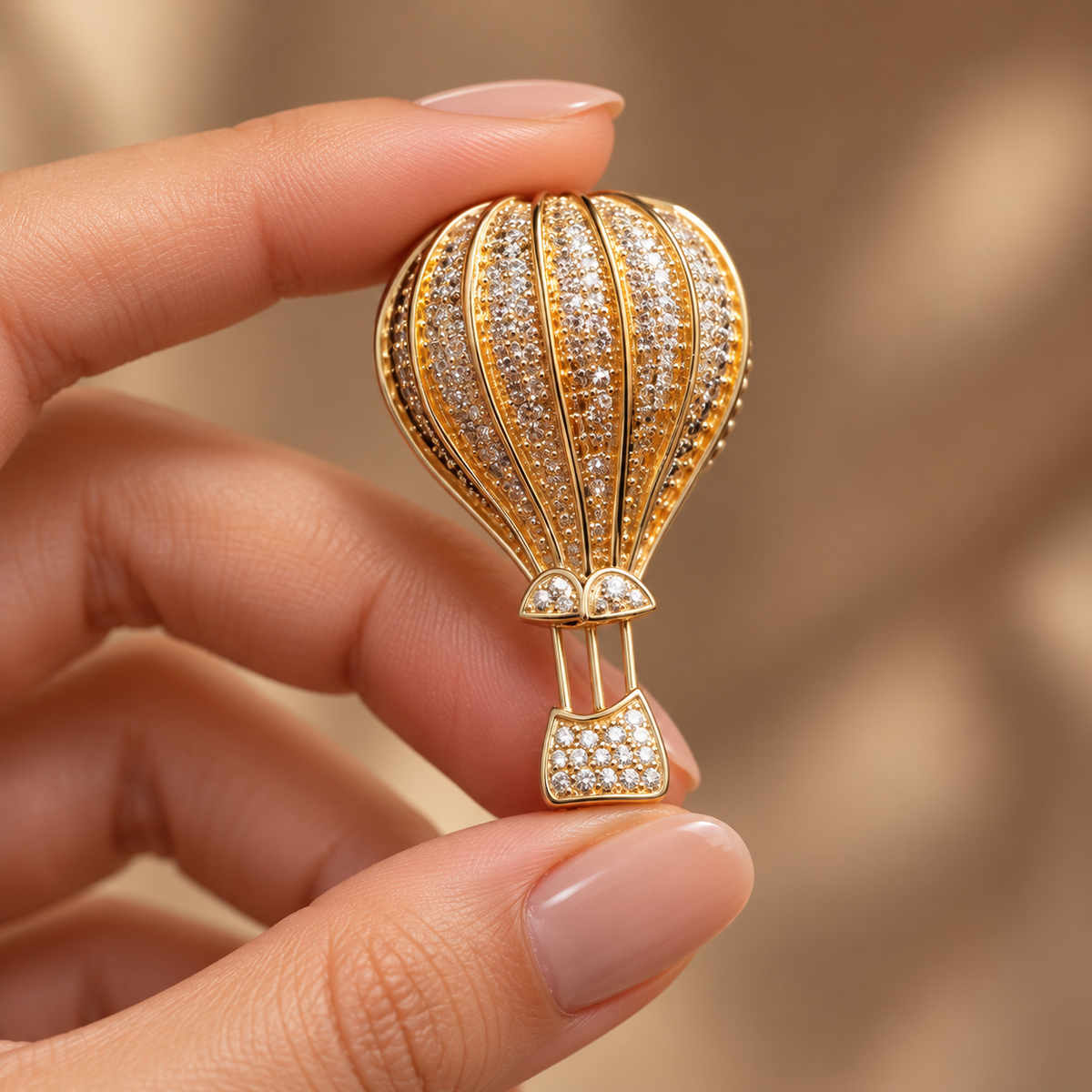 Gold hot air balloon brooch and pendant held in a hand