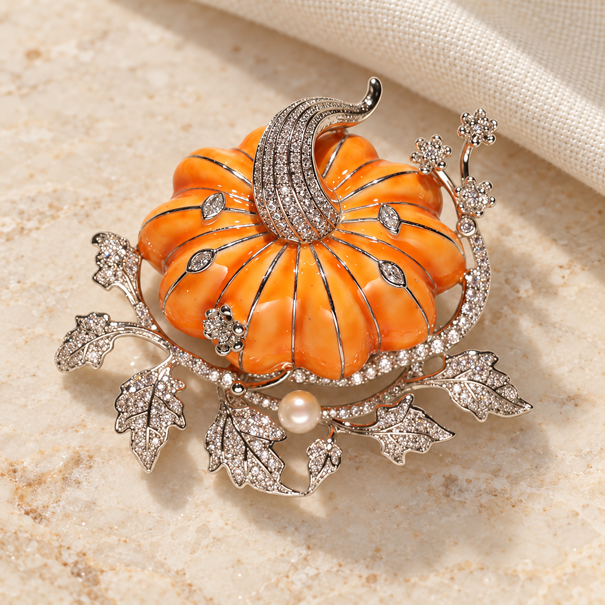Orange pumpkin brooch in a styled tabletop display, shared design illustration