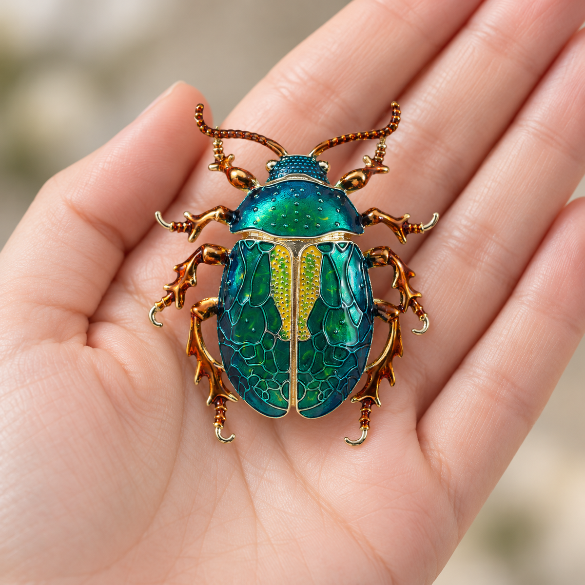 Dark Green enamel beetle brooch, held in a hand