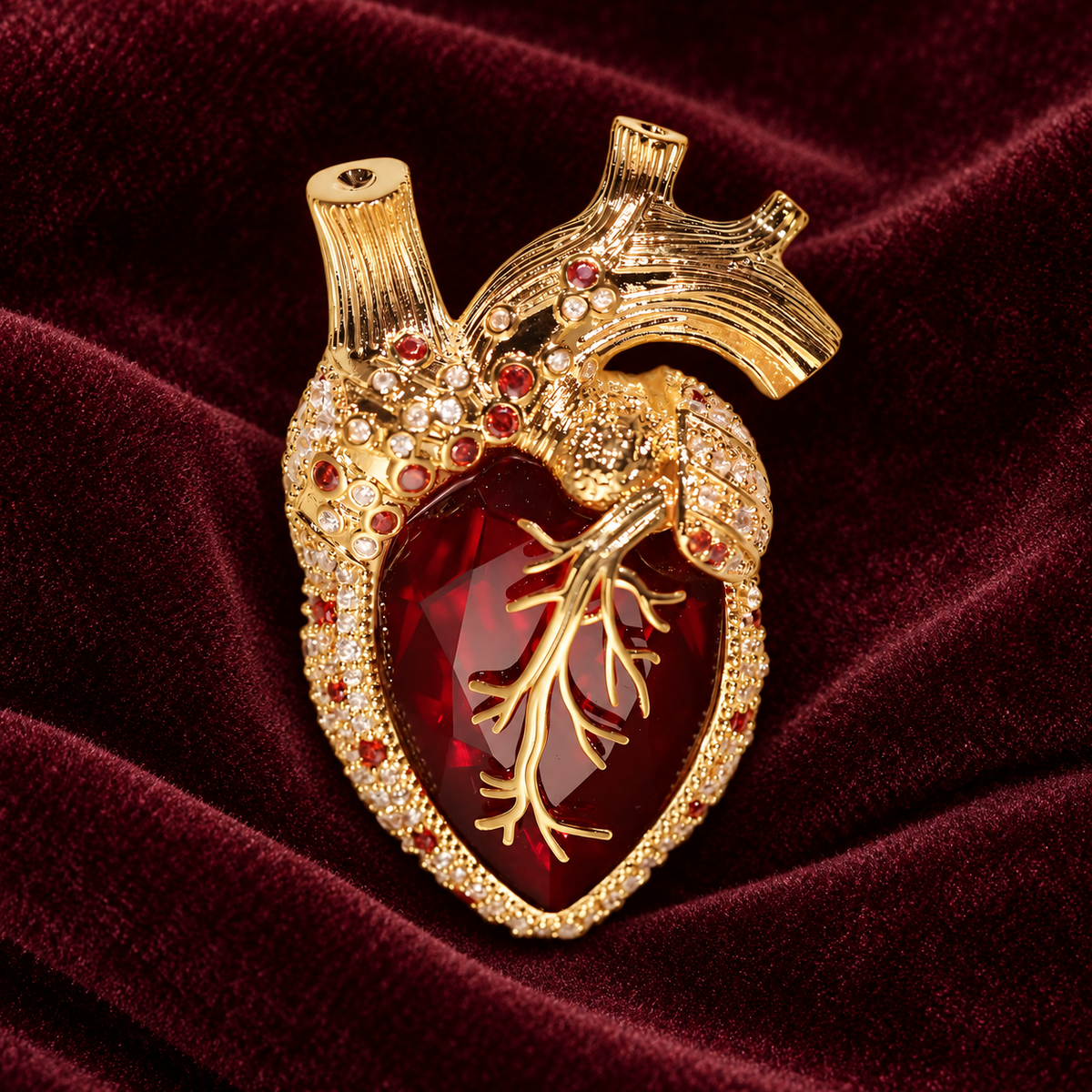 Gold tone red anatomical heart brooch on a dark background