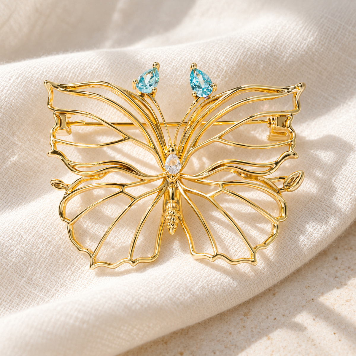 Sea Blue openwork butterfly brooch displayed on ivory fabric
