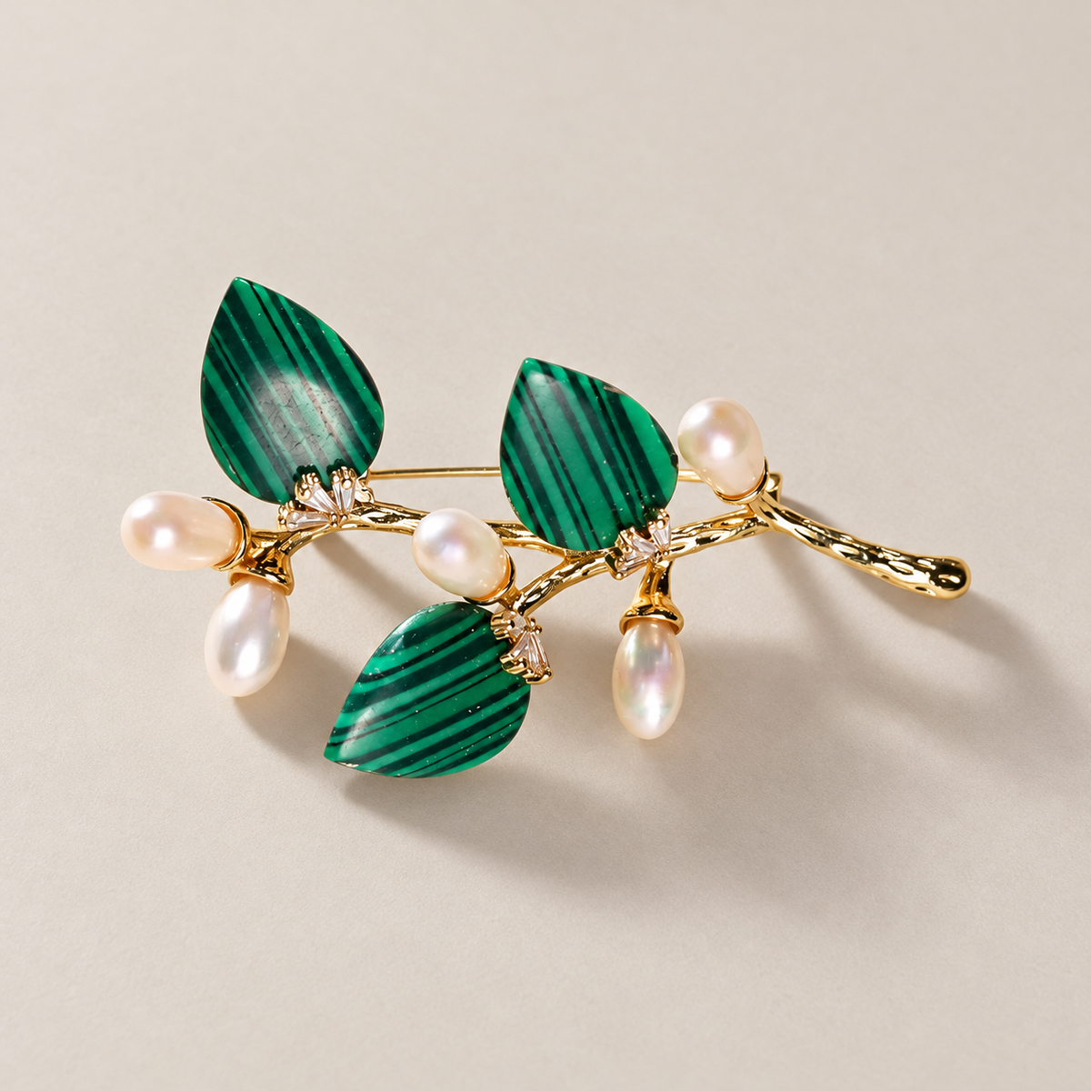 Green natural stone flower branch brooch with freshwater pearls on a neutral background