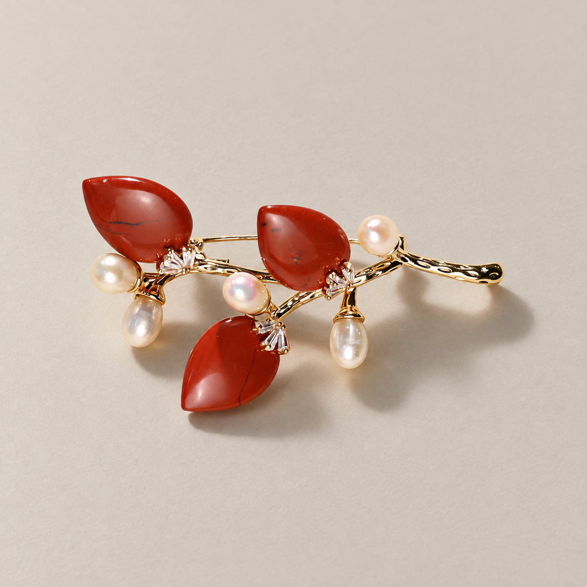 Red natural stone flower branch brooch with freshwater pearls on a neutral background
