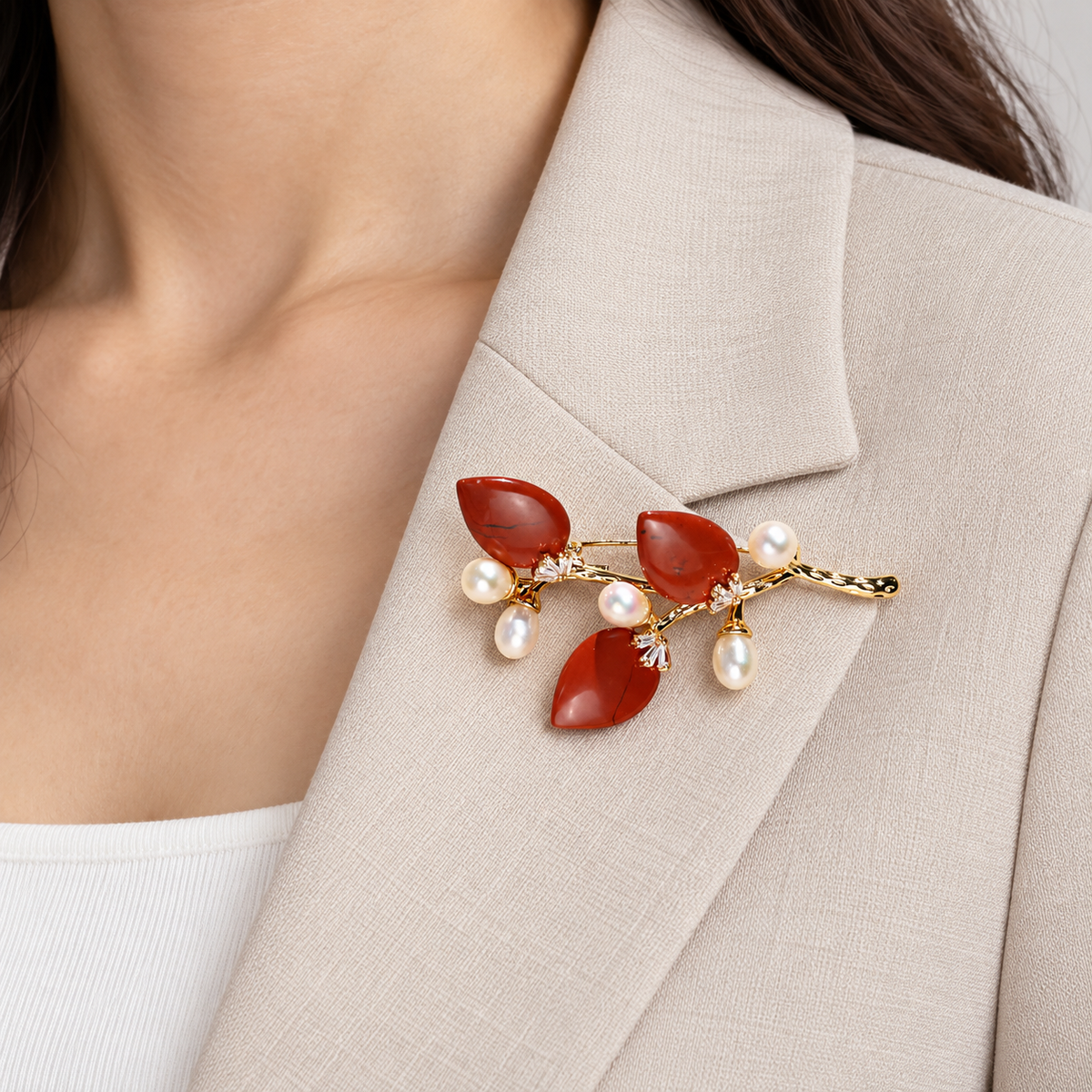 Red natural stone flower branch brooch with freshwater pearls worn on a blazer lapel