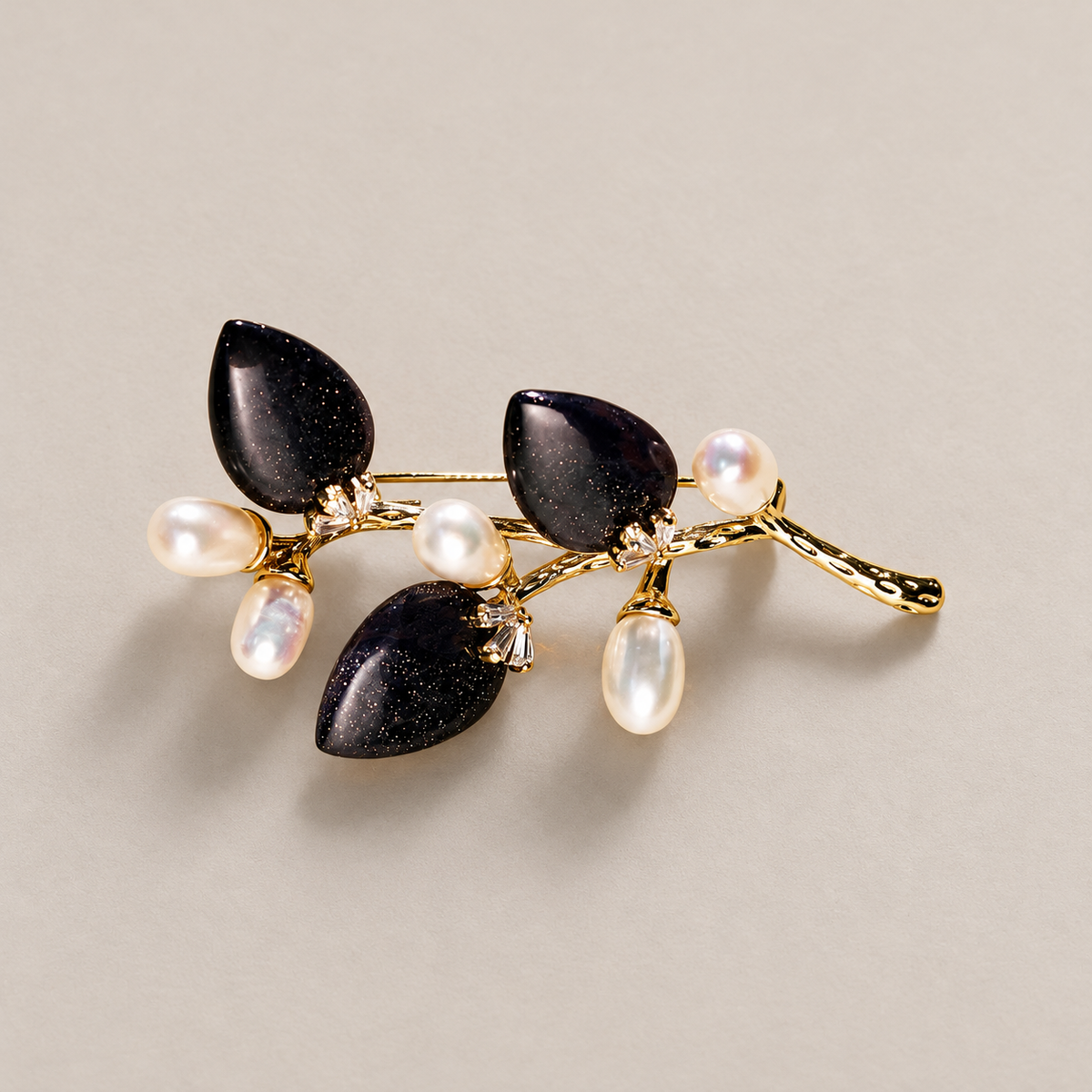 Black natural stone flower branch brooch with freshwater pearls on a neutral background