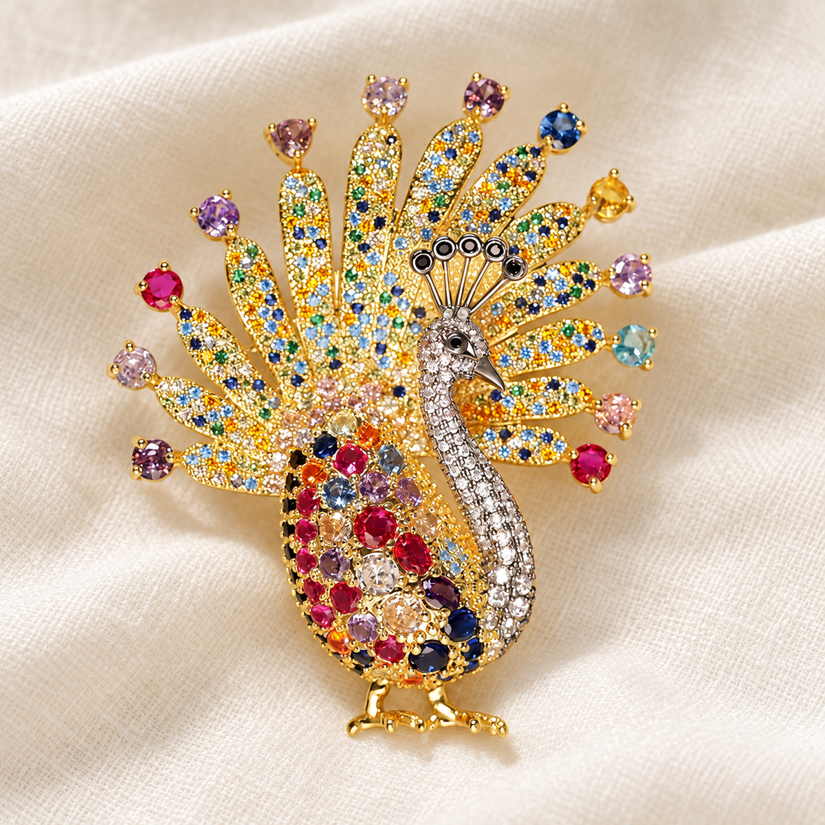 Gold-tone white-neck peacock brooch on a soft fabric tabletop