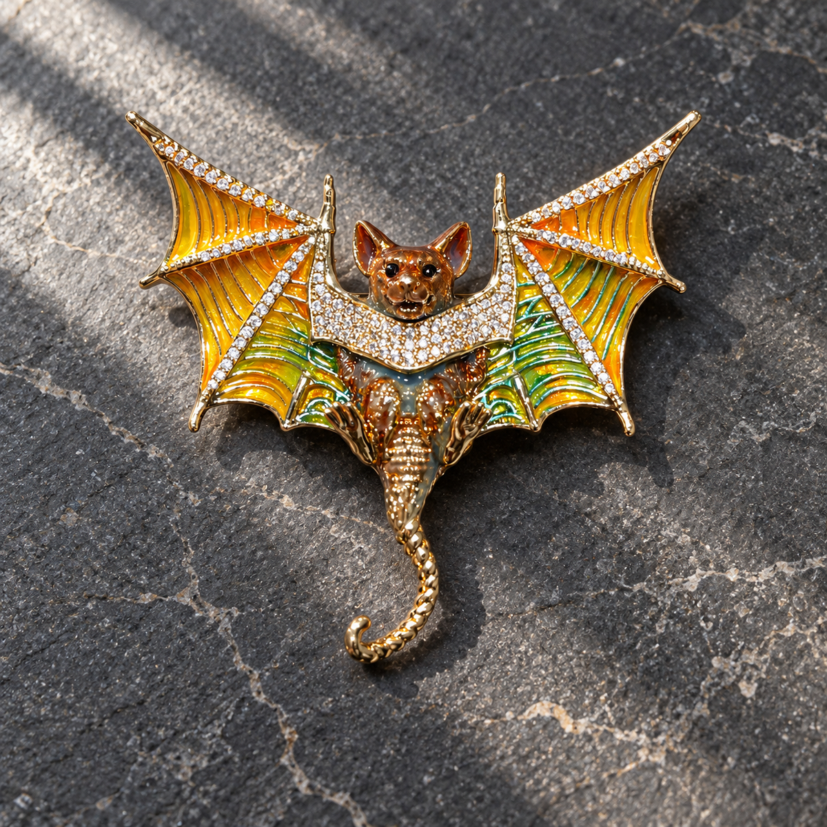 Colorful copper bat brooch with orange and green wings and curled tail, tabletop view