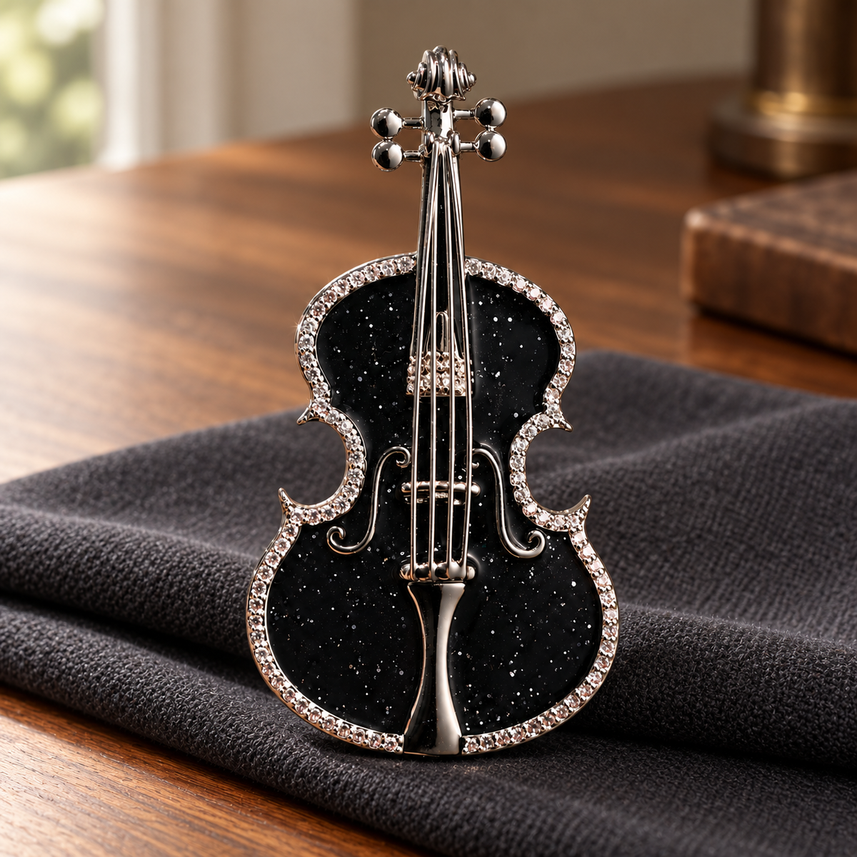 Black violin brooch displayed on charcoal fabric over a wooden table
