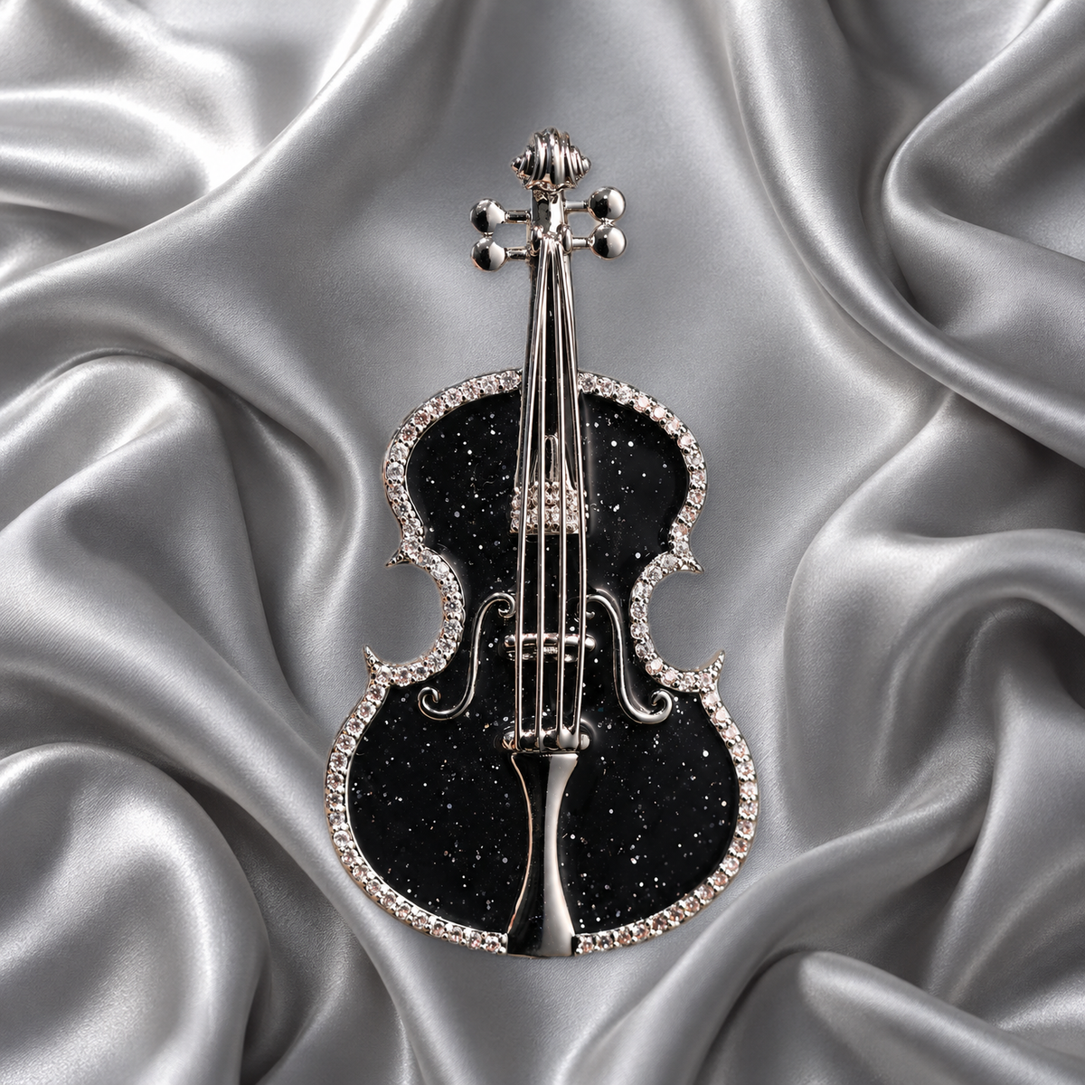Black violin brooch with silver-tone outline and string details on silver-grey satin