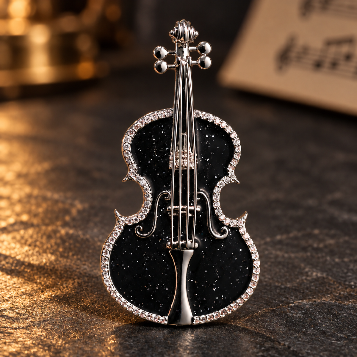 Black violin brooch on a dark tabletop with warm lighting