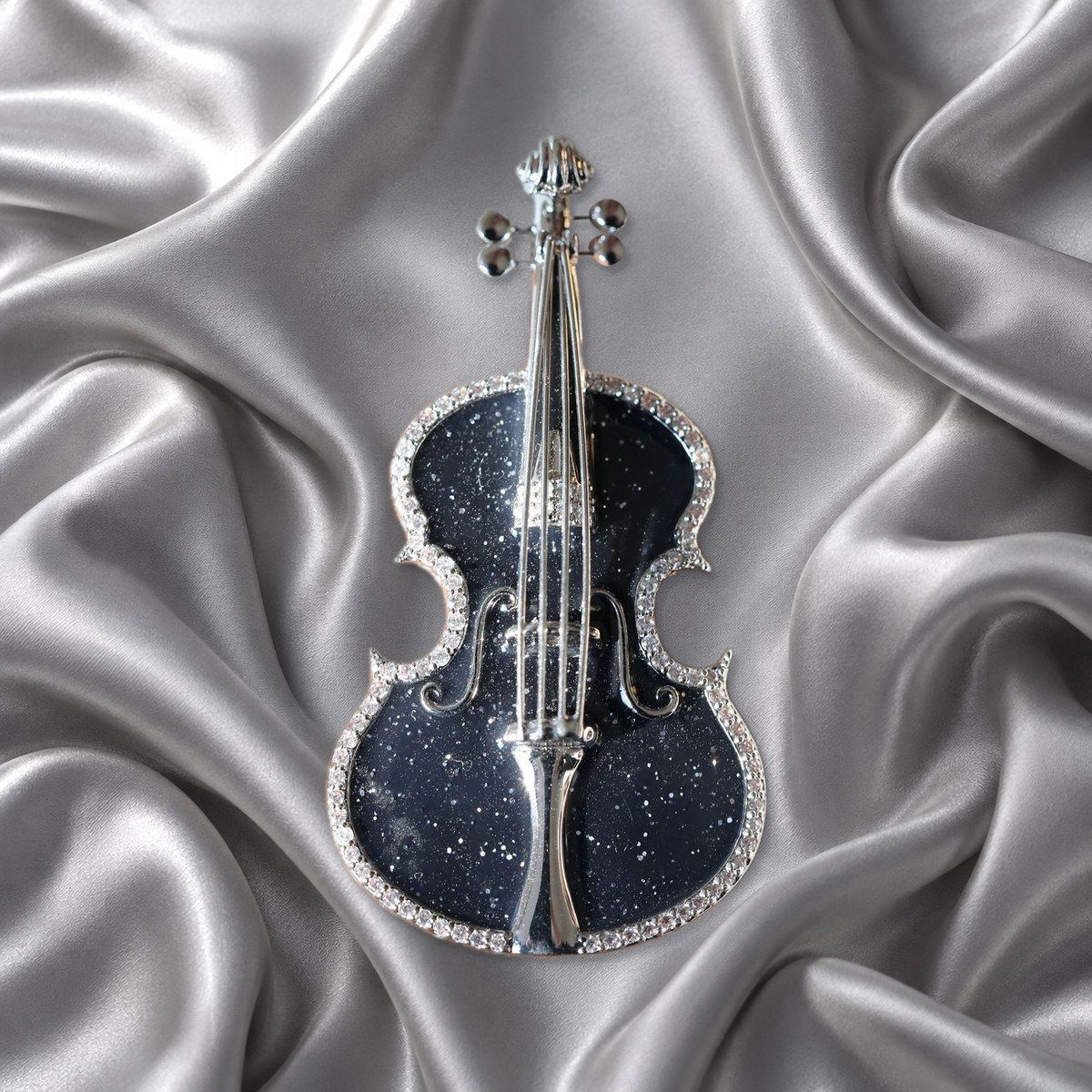 Black violin brooch with silver-tone details on silver-grey satin