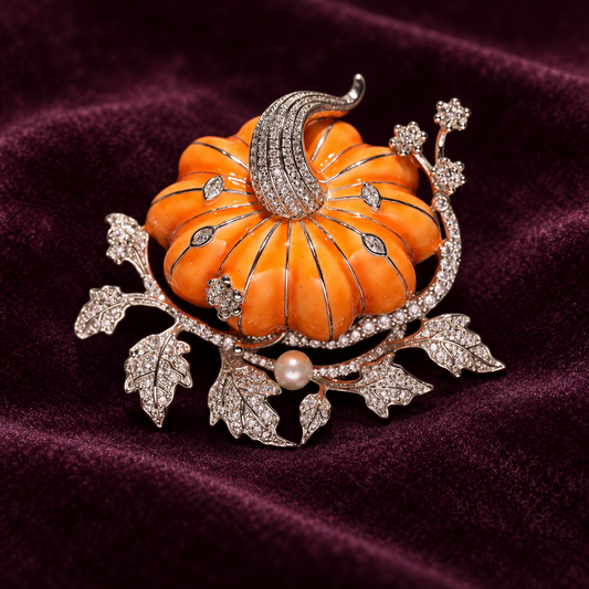 Orange pumpkin brooch with a curved silver-tone stem, leafy vine and a pale pearl accent