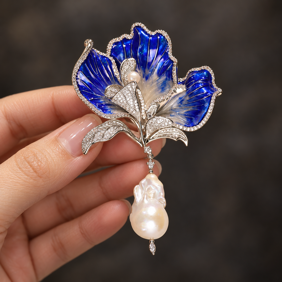 Blue with Baroque Pearl canna flower brooch held in a hand