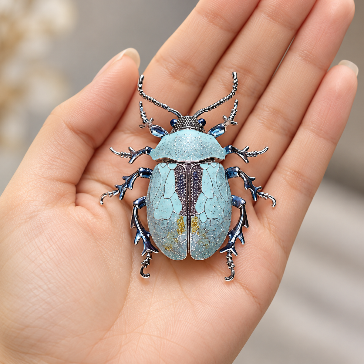 Blue enamel beetle brooch, held in a hand