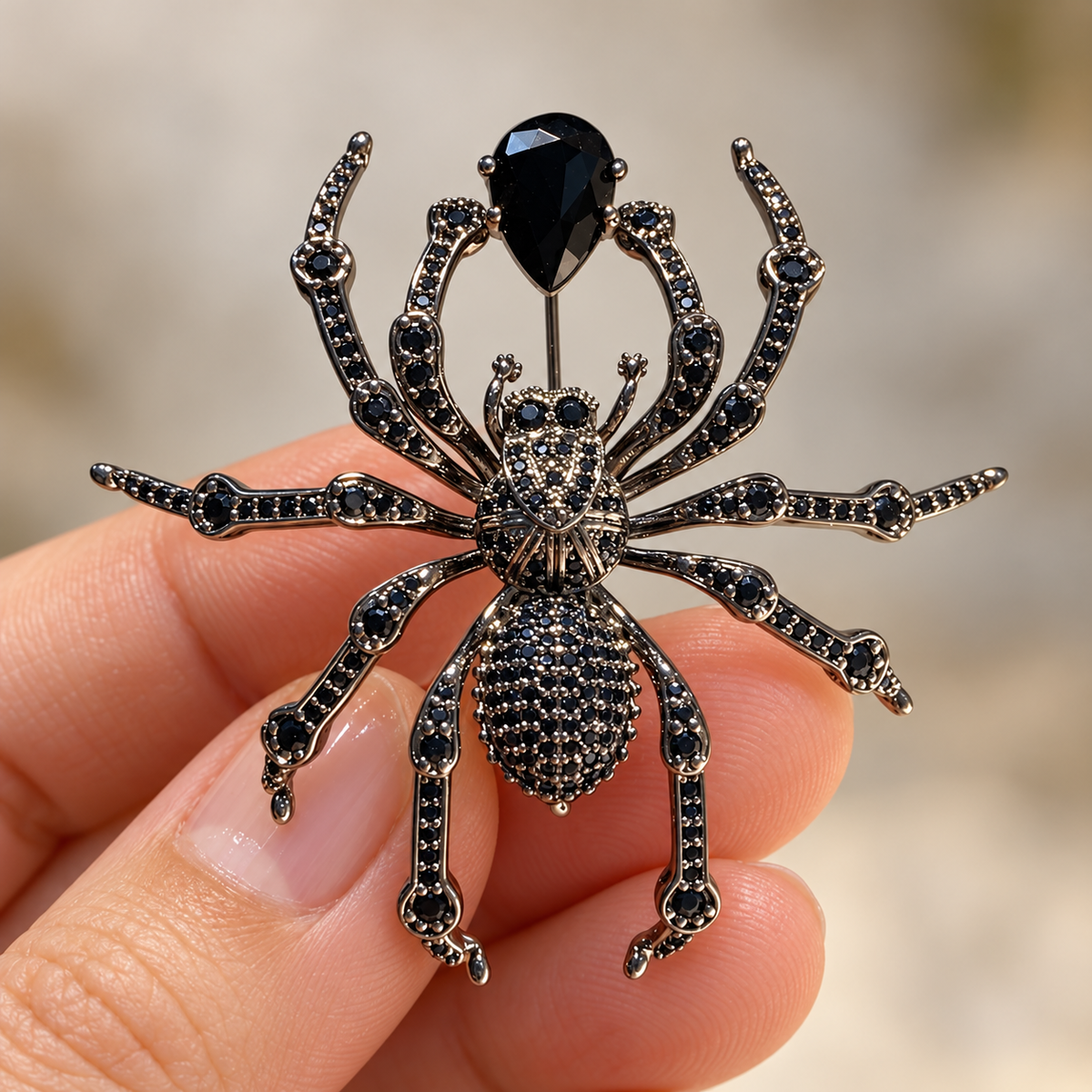 Gunmetal Tone spider brooch held in a hand