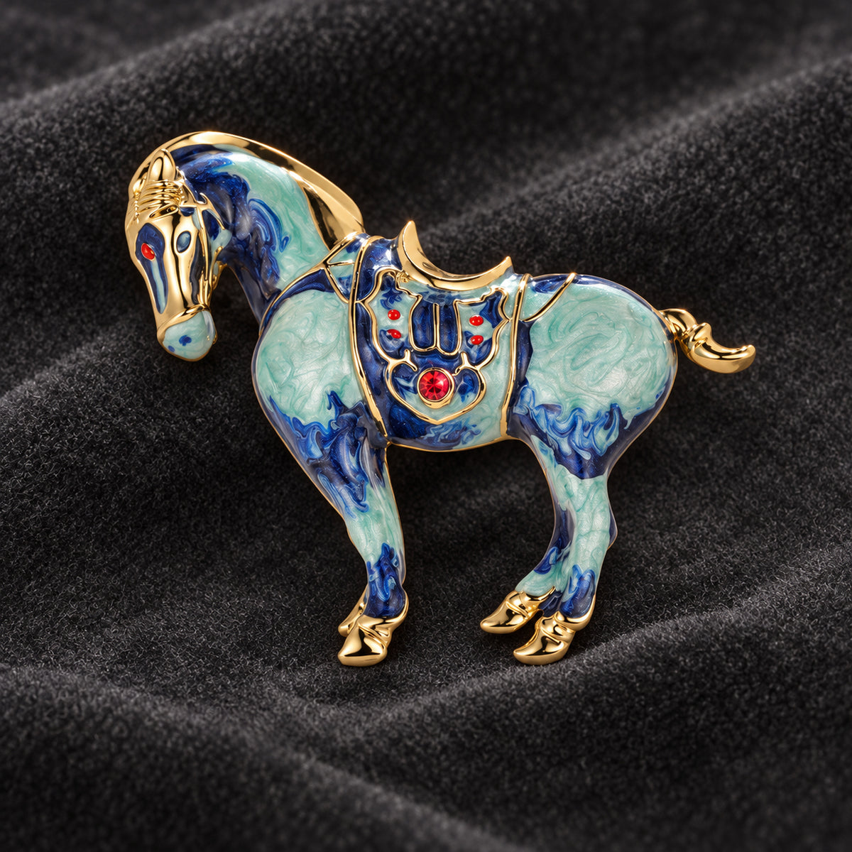 Blue horse brooch with colorful decorative detailing on dark velvet