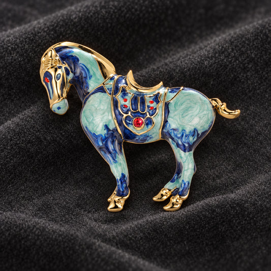 Blue horse brooch with colorful decorative detailing on dark velvet
