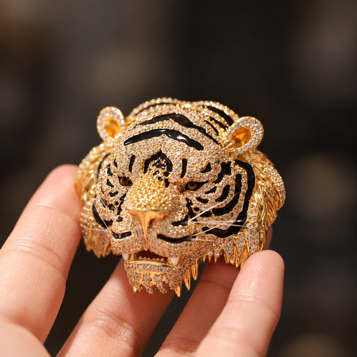 Gold-tone tiger head brooch held in a hand