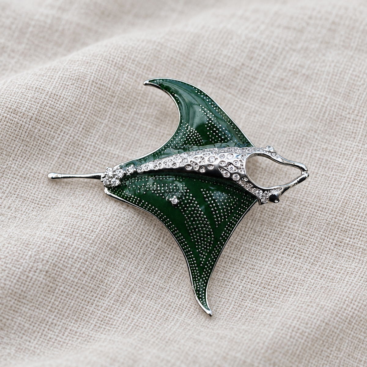 Green enamel manta ray brooch in a tabletop setting