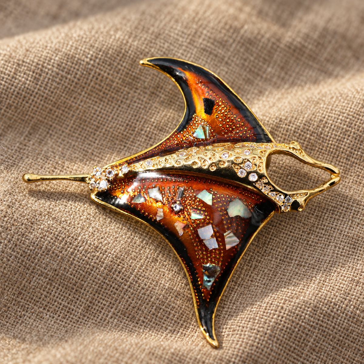 Orange enamel manta ray brooch in a tabletop setting