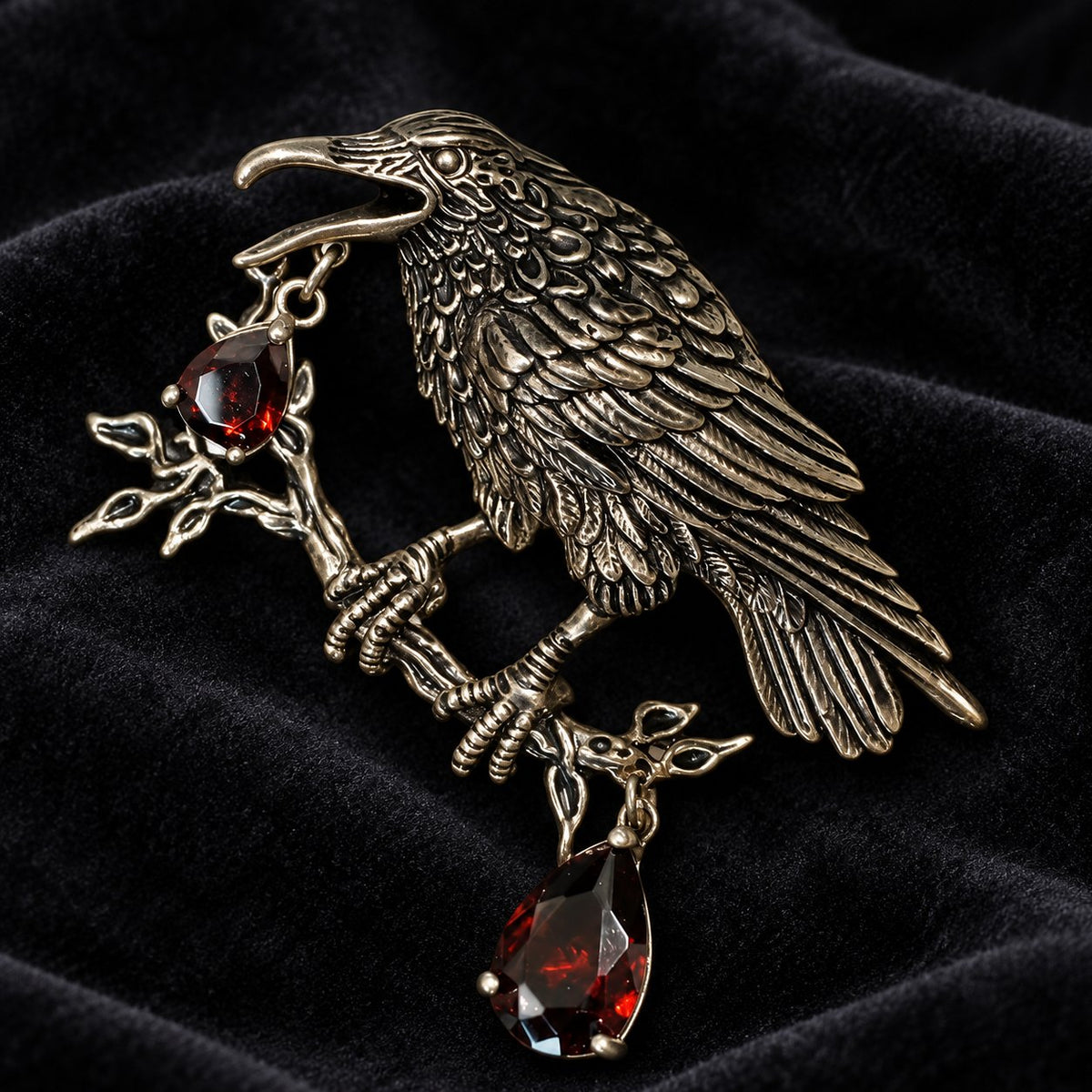 Dark raven brooch with layered feathers, a branch and burgundy-red drops