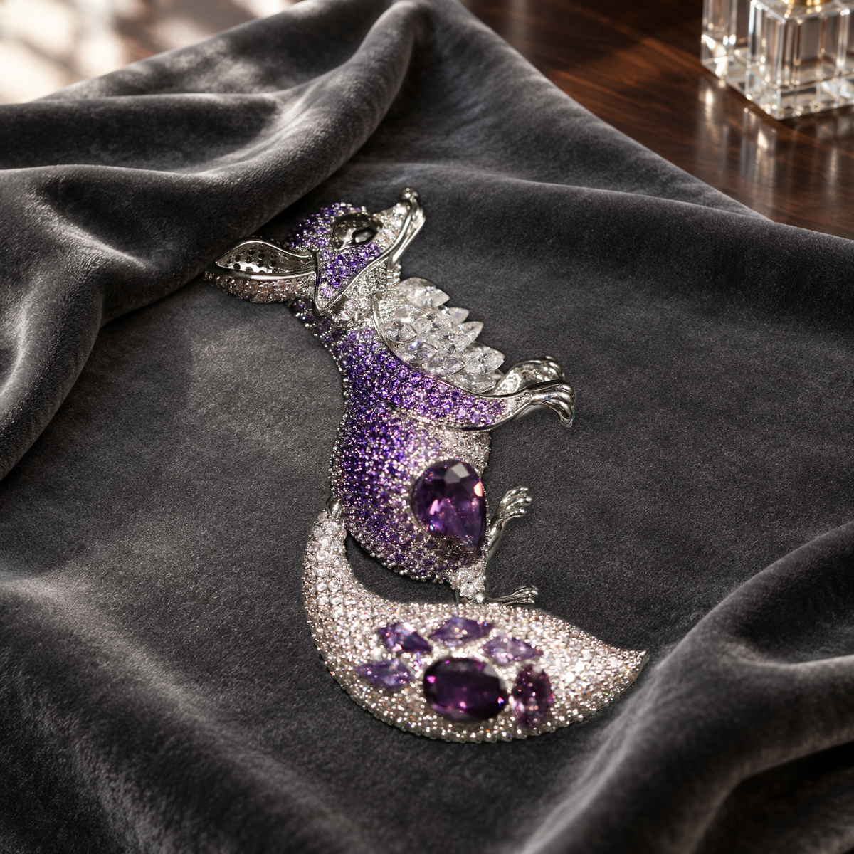 Purple and silver-tone fox brooch resting on charcoal velvet on a dressing table.