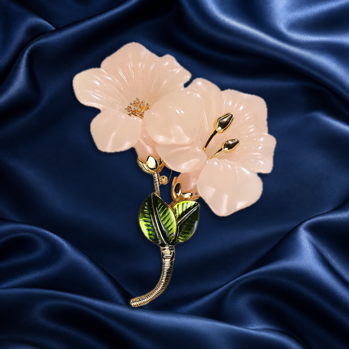 Pale pink flower brooch with gold-tone centers on navy satin