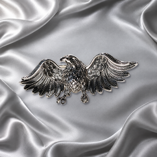 Silver-tone eagle brooch with sculpted spread wings on silver satin