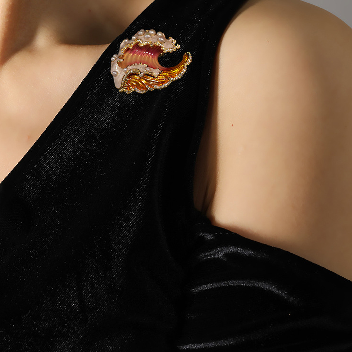Orange enamel wave brooch worn on a black garment, shown in its original wearing context.