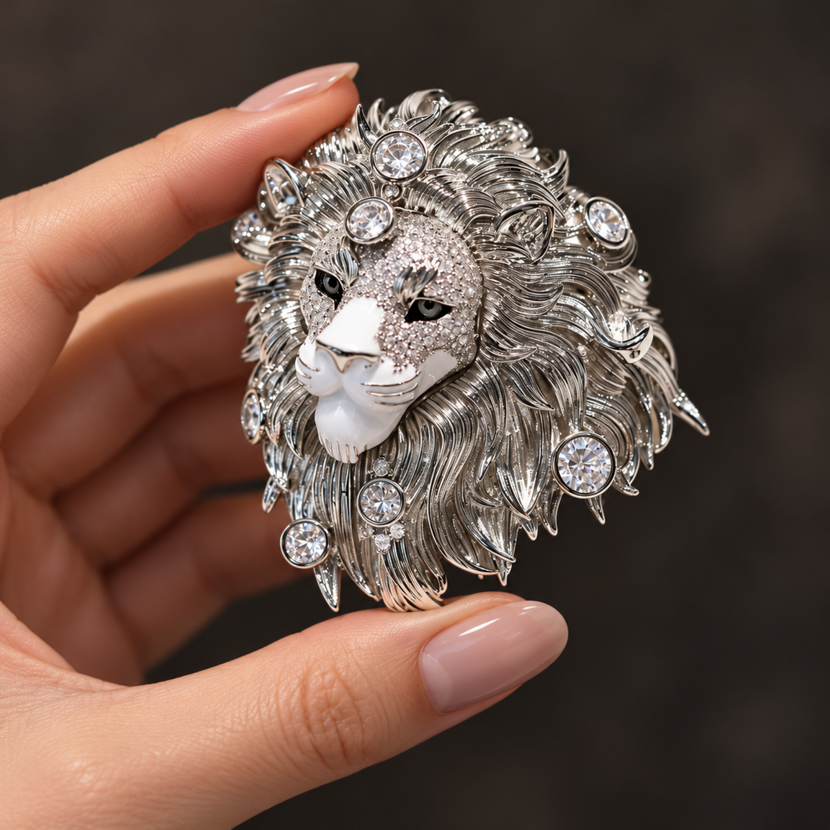 Silver tone lion head brooch held in a hand